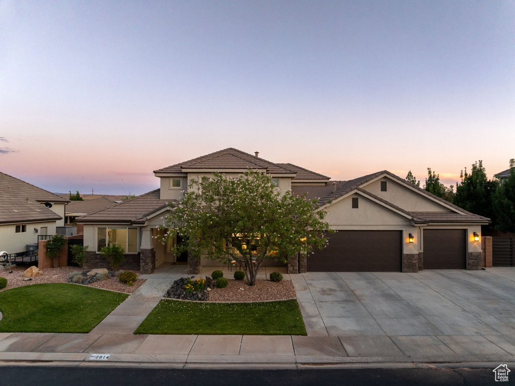View of front facade with a garage, concrete driveway, stone siding, and stucco siding