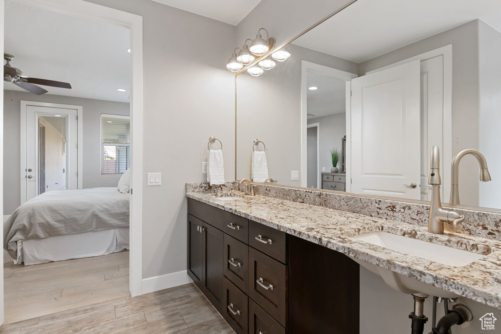 Ensuite bathroom with wood finished floors, double vanity, ceiling fan, baseboards, and recessed lighting