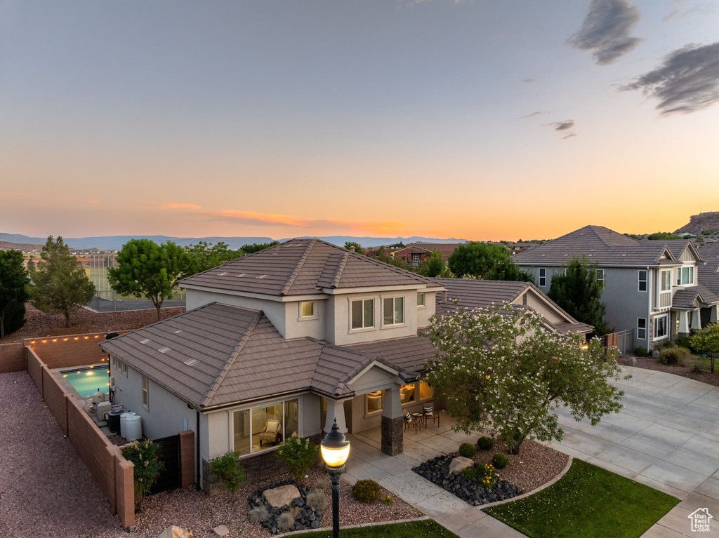 View of front of house with stucco siding, a tile roof, concrete driveway, a fenced backyard, and a patio