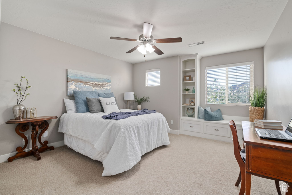 Bedroom with light colored carpet, an office area, baseboards, and a ceiling fan