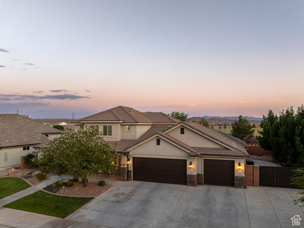 View of front of property featuring driveway, a garage, a tile roof, and stone siding