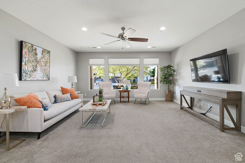 Carpeted living area with ceiling fan, baseboards, and recessed lighting
