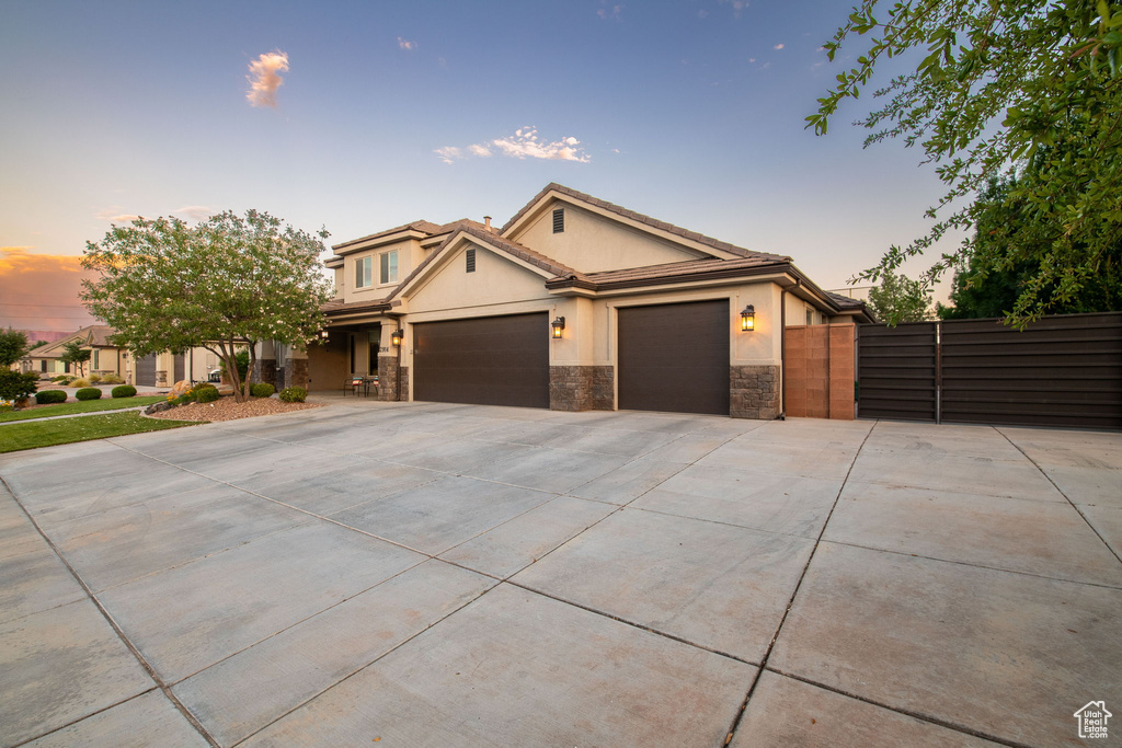 View of front of property featuring stucco siding, an attached garage, concrete driveway, and stone siding
