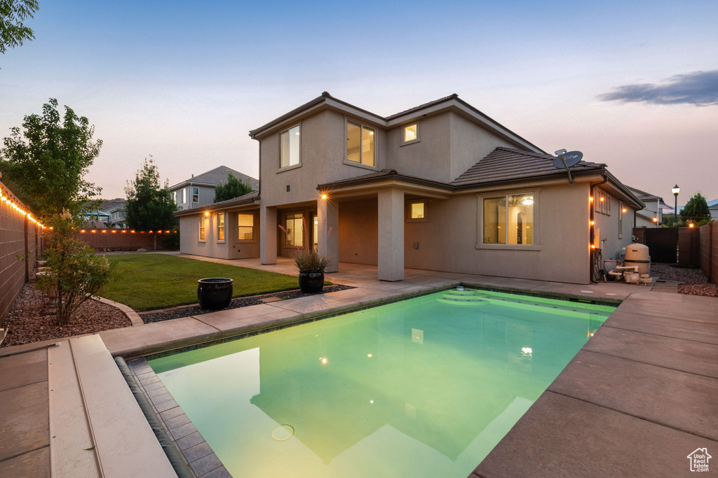 Back of property at dusk with a patio and stucco siding
