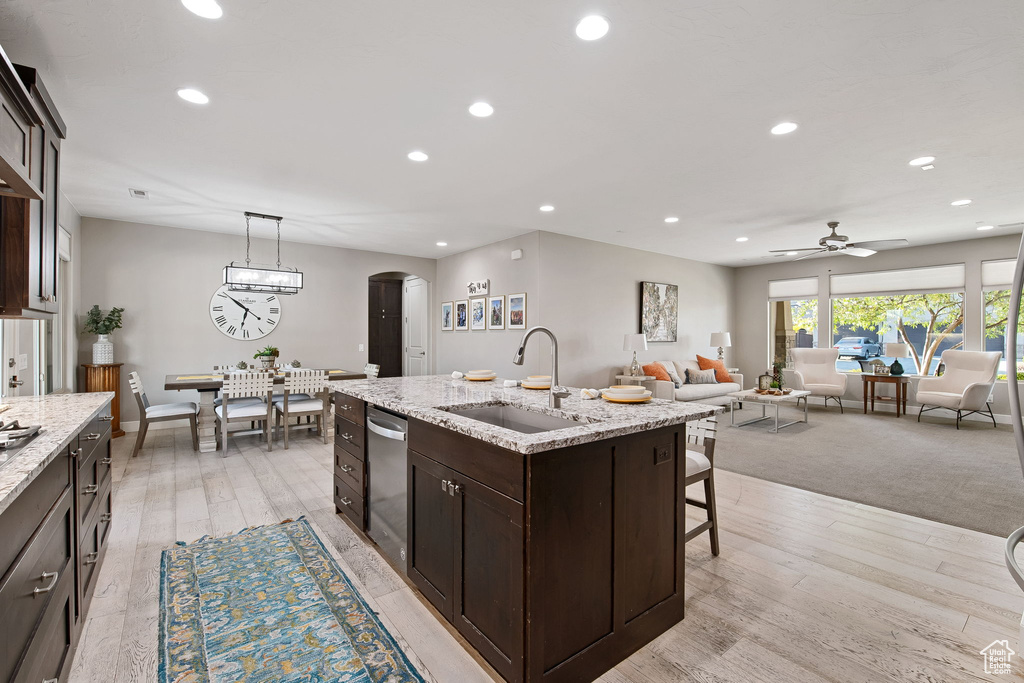 Kitchen with a sink, arched walkways, stainless steel dishwasher, dark brown cabinets, and recessed lighting