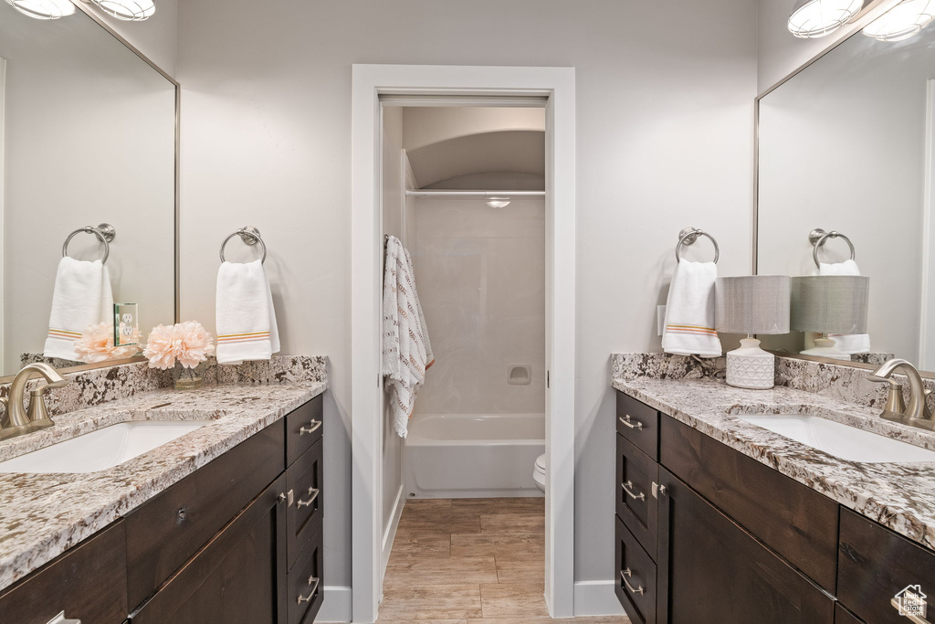 Bathroom with vanity, baseboards, bathtub / shower combination, and toilet