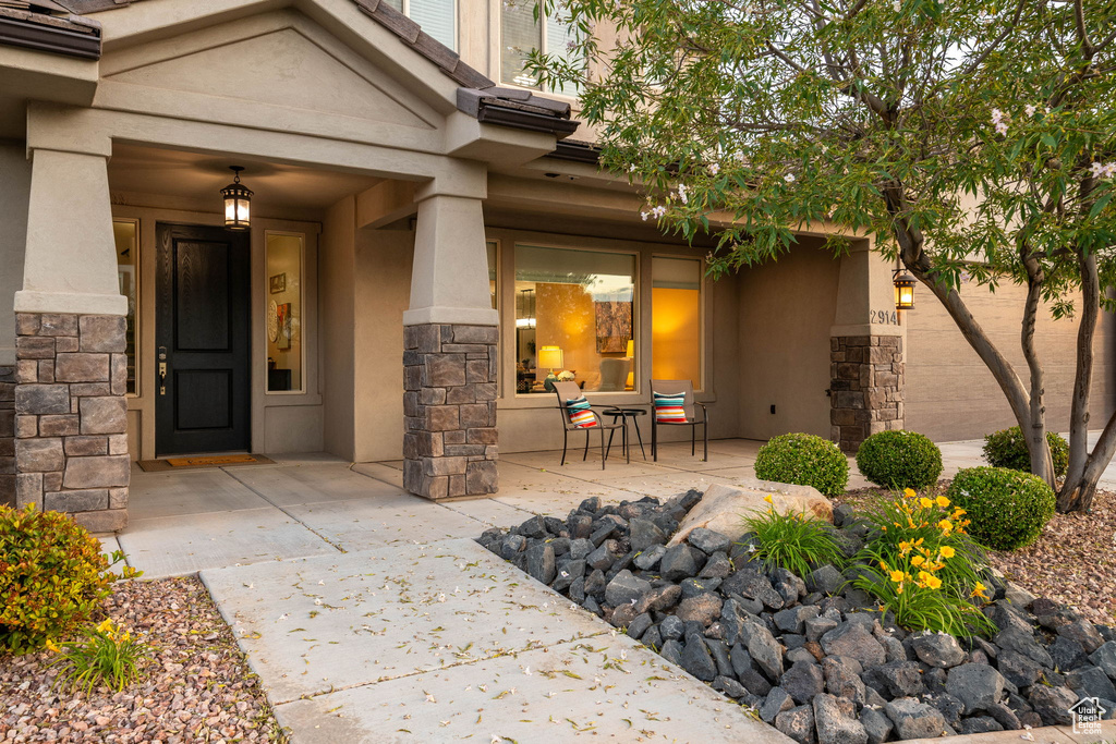 View of exterior entry with stucco siding, stone siding, and covered porch