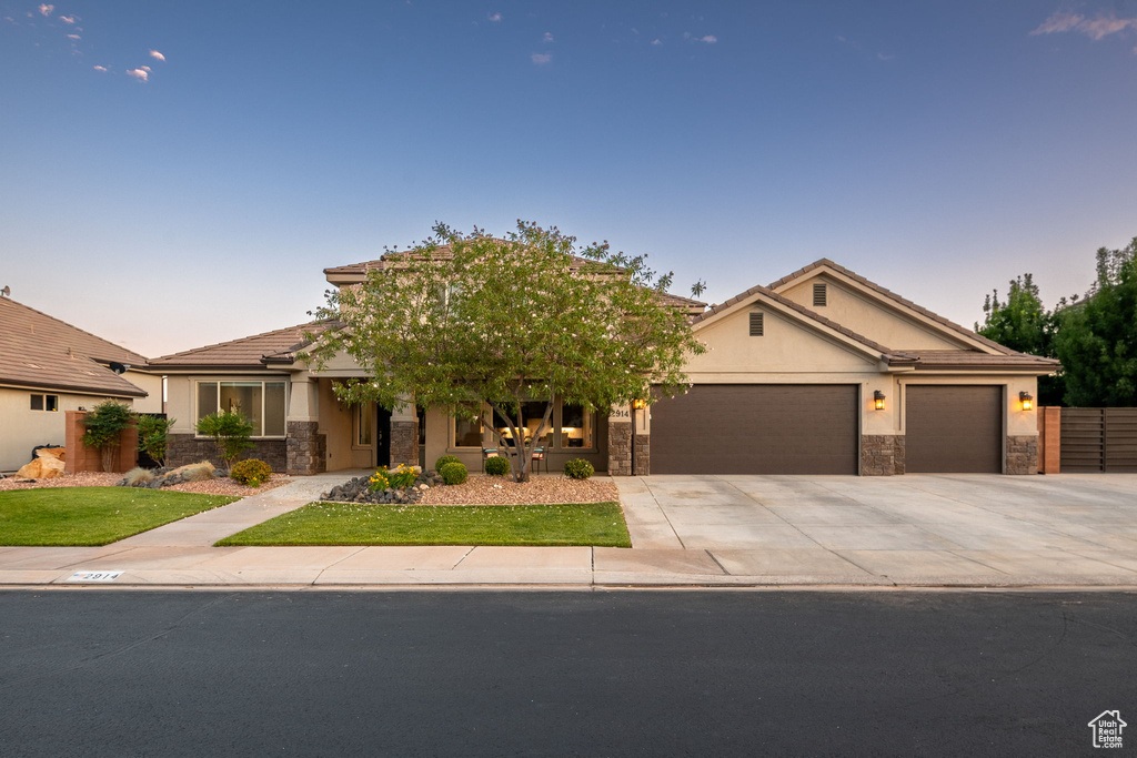 View of front of property featuring stone siding, an attached garage, concrete driveway, stucco siding, and a tile roof