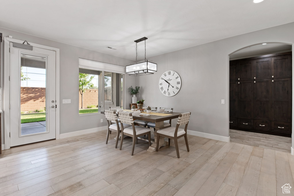 Dining room featuring arched walkways, light wood-style flooring, baseboards, and a chandelier