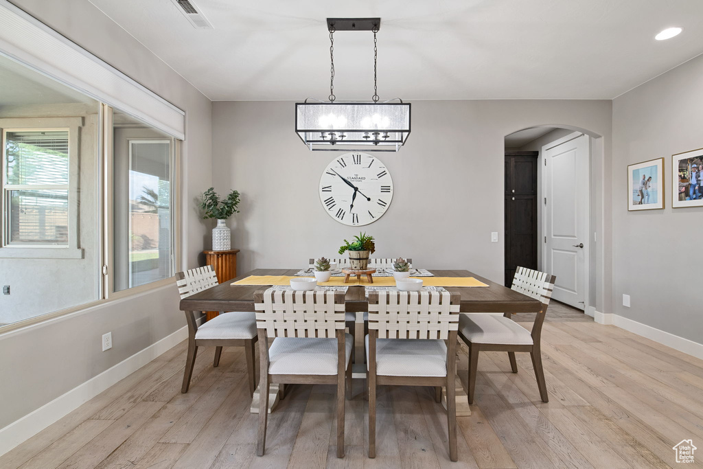 Dining area featuring arched walkways, light wood finished floors, baseboards, recessed lighting, and a chandelier