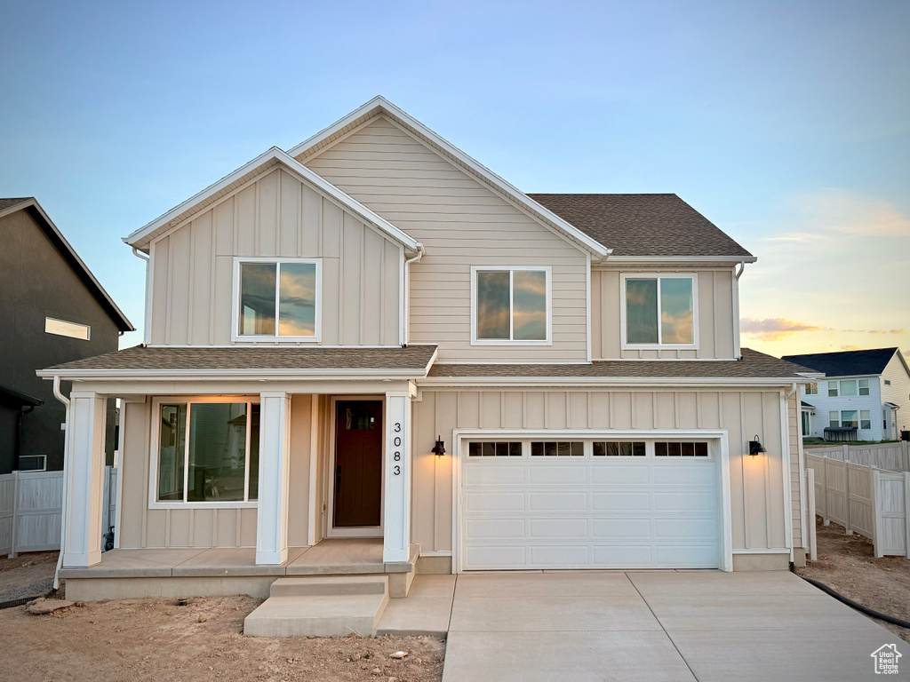 Traditional home with a porch, board and batten siding, driveway, and a garage