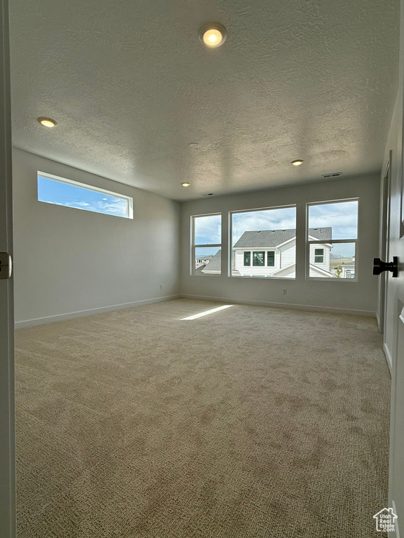 Carpeted empty room with a textured ceiling and recessed lighting