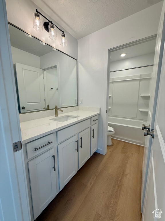 Bathroom featuring wood finished floors, vanity, shower / tub combination, and a textured ceiling