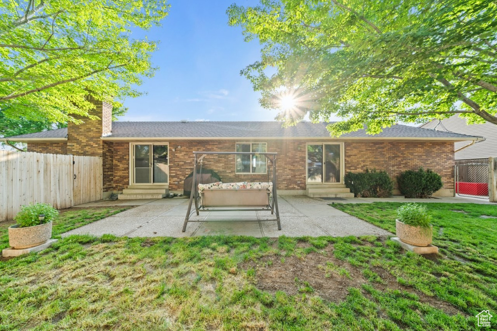 Rear view of property with entry steps, a patio area, a shingled roof, and a chimney