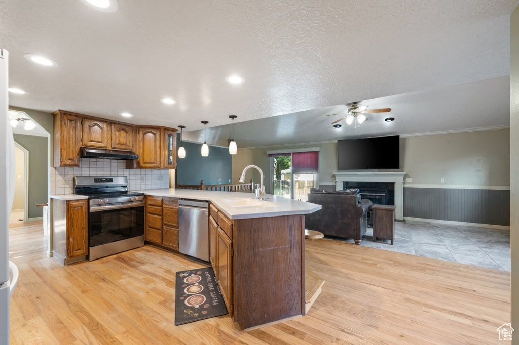 Kitchen with stainless steel appliances, a peninsula, a sink, ceiling fan, and brown cabinets