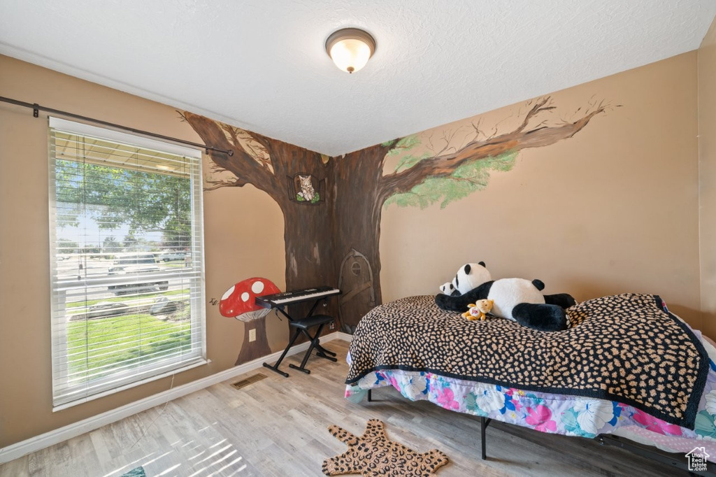 Bedroom with multiple windows, wood finished floors, and baseboards