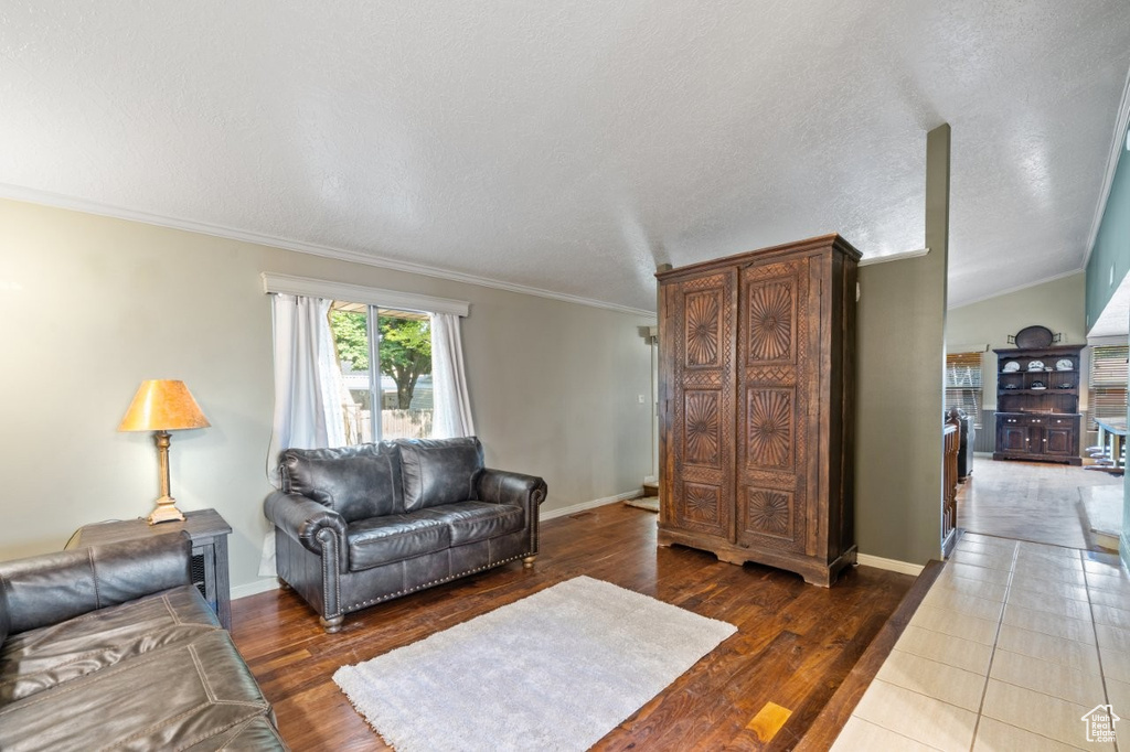 Living room with crown molding, wood finished floors, baseboards, and a textured ceiling