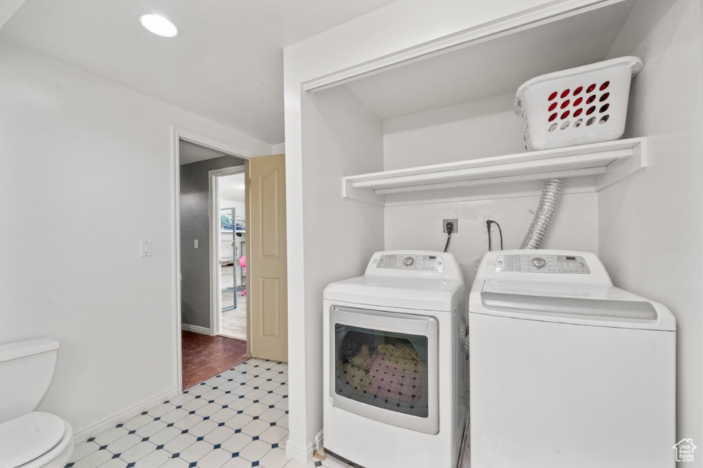 Laundry room with washing machine and dryer, light floors, and baseboards