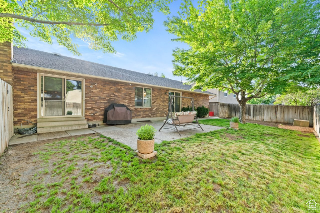 Back of house with a patio, roof with shingles, and brick siding
