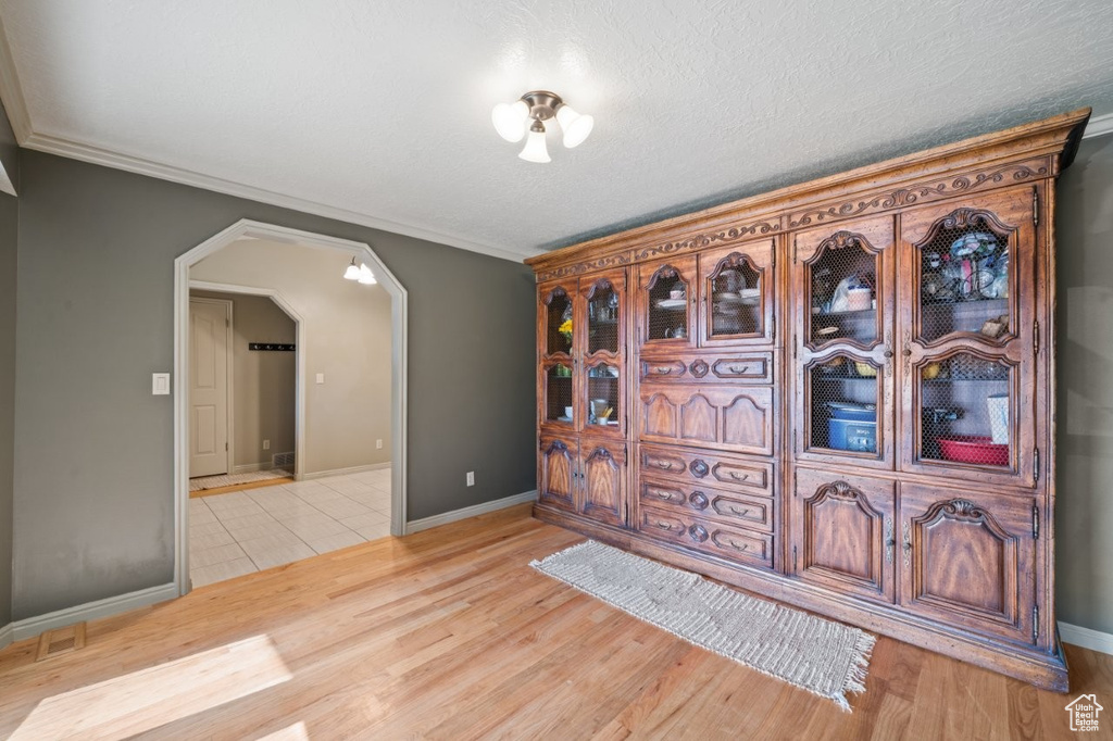 Foyer entrance featuring arched walkways, light wood-style floors, baseboards, and crown molding