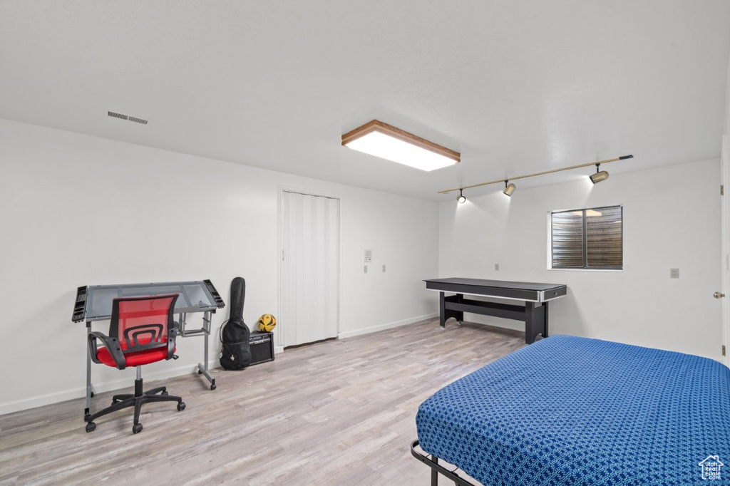 Bedroom with wood finished floors, rail lighting, and baseboards