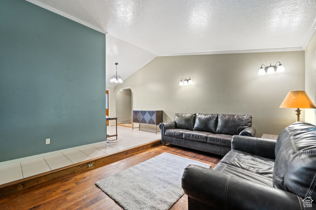 Living area featuring hardwood / wood-style floors, arched walkways, lofted ceiling, a textured ceiling, and baseboards