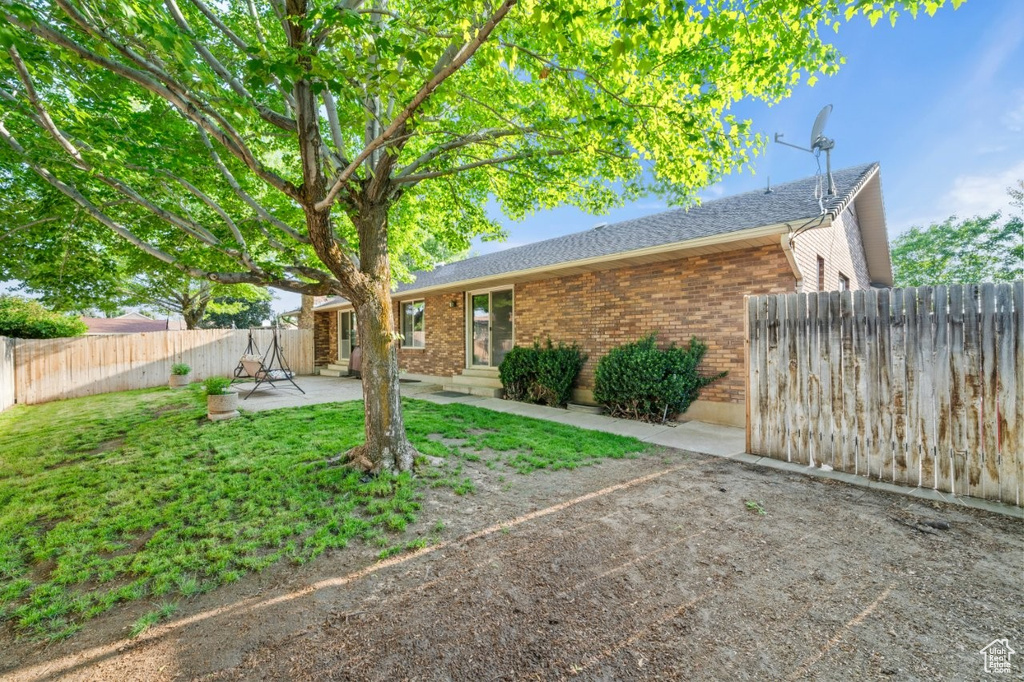 Rear view of property with brick siding, a patio, entry steps, and roof with shingles