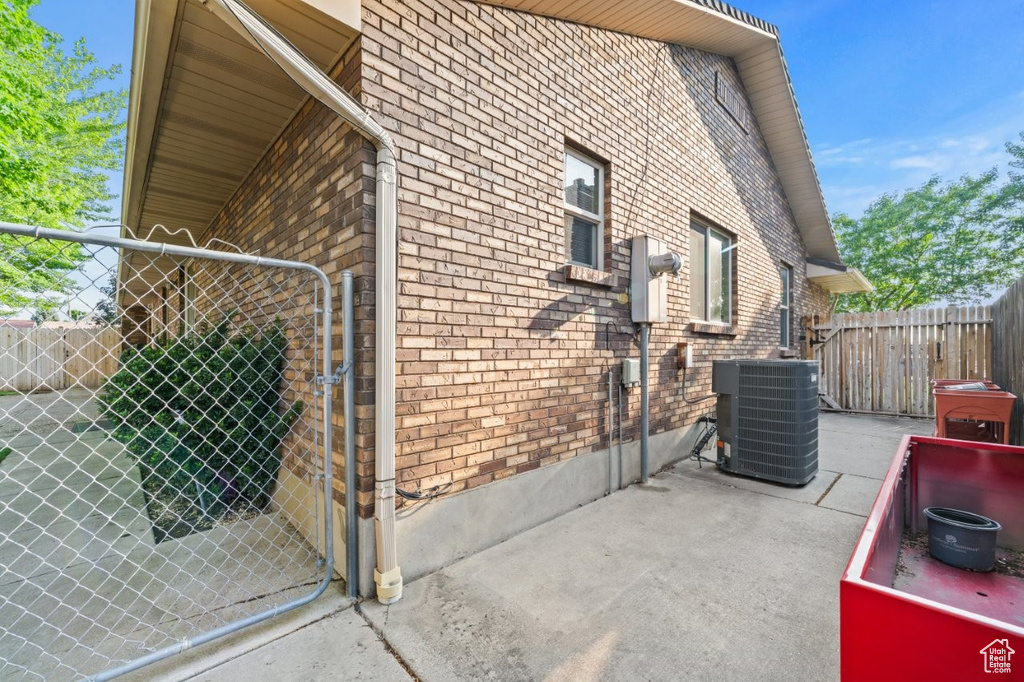 View of side of home featuring central air condition unit, a gate, and brick siding