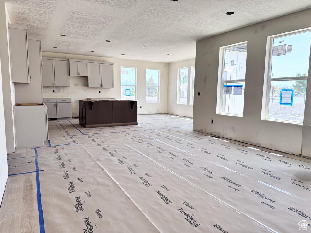 Kitchen featuring a textured ceiling, gray cabinets, open floor plan, and a kitchen island
