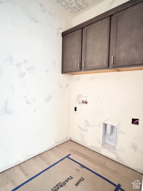 Washroom with cabinet space, light wood finished floors, and washer hookup