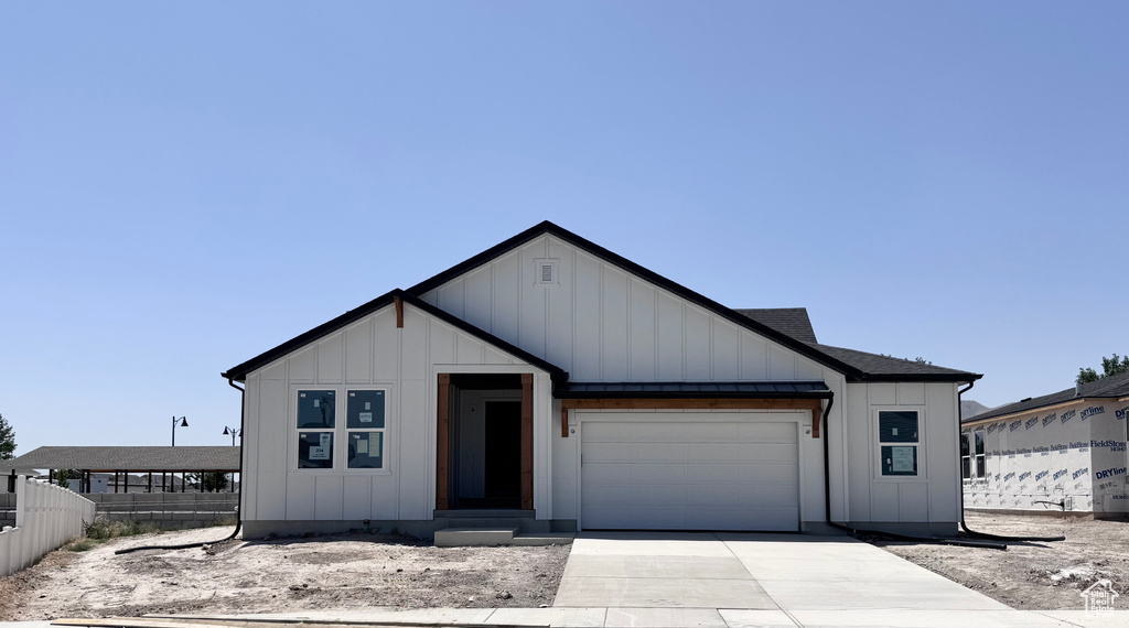 Modern farmhouse with board and batten siding, driveway, and an attached garage