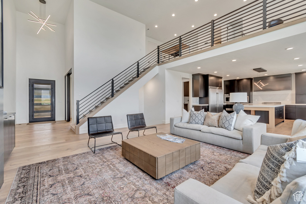 Living area featuring a high ceiling, stairs, light wood finished floors, and recessed lighting