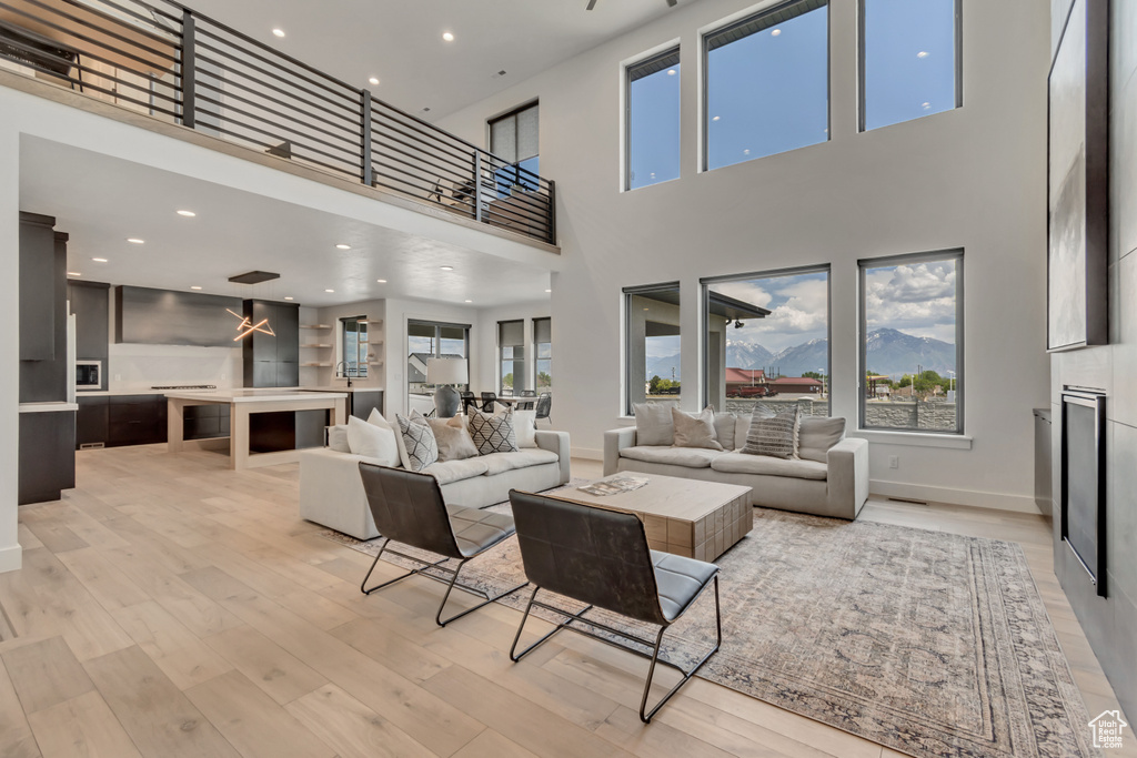 Living area with light wood-style floors, a high ceiling, baseboards, and recessed lighting