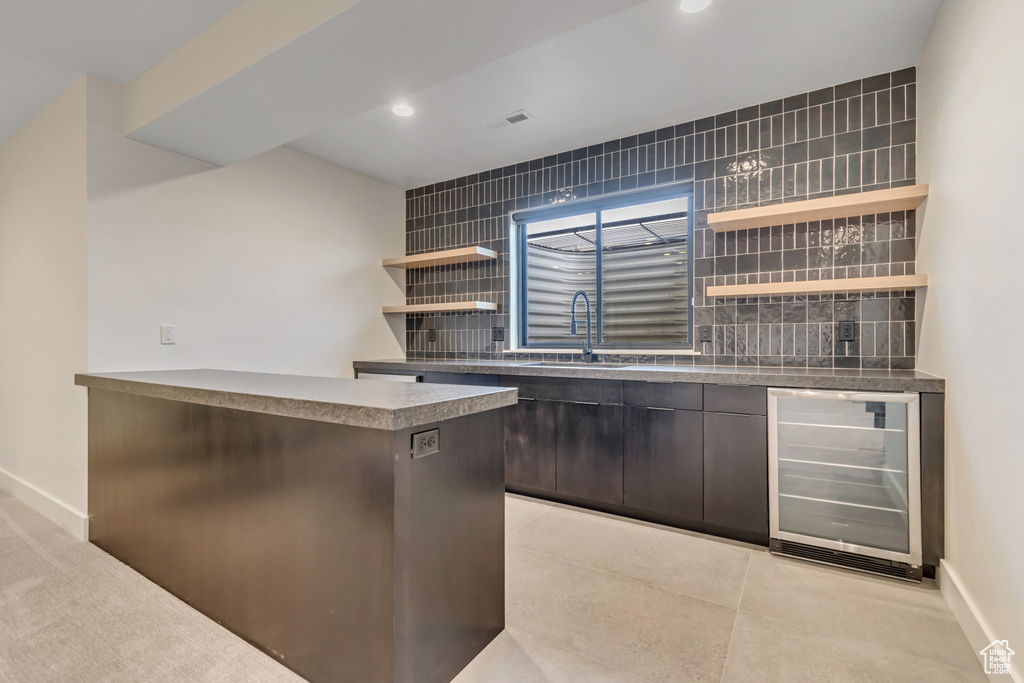 Bar area featuring beverage cooler, a sink, decorative backsplash, baseboards, and recessed lighting