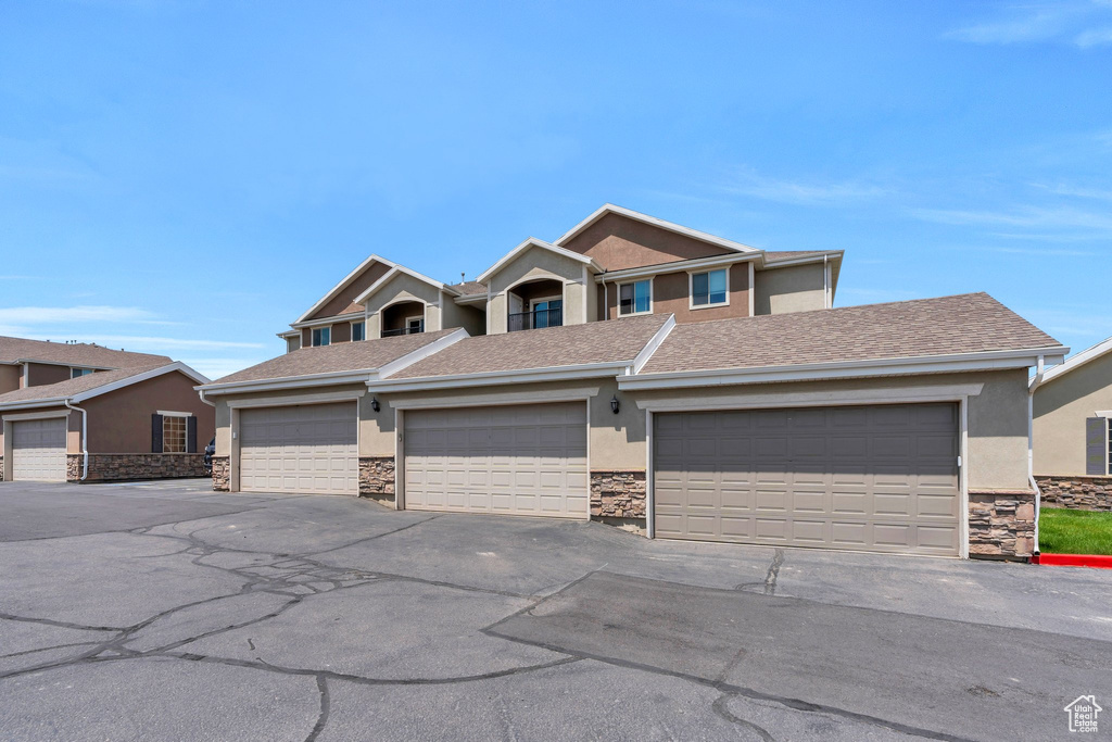 View of front of home featuring stucco siding, stone siding, and a shingled roof
