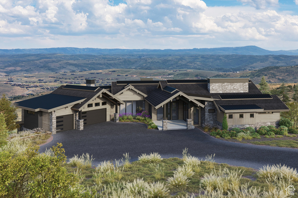 View of front of home featuring stone siding, an attached garage, a mountain view, and asphalt driveway