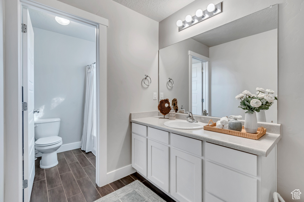 Bathroom featuring vanity, toilet, baseboards, and a shower with curtain