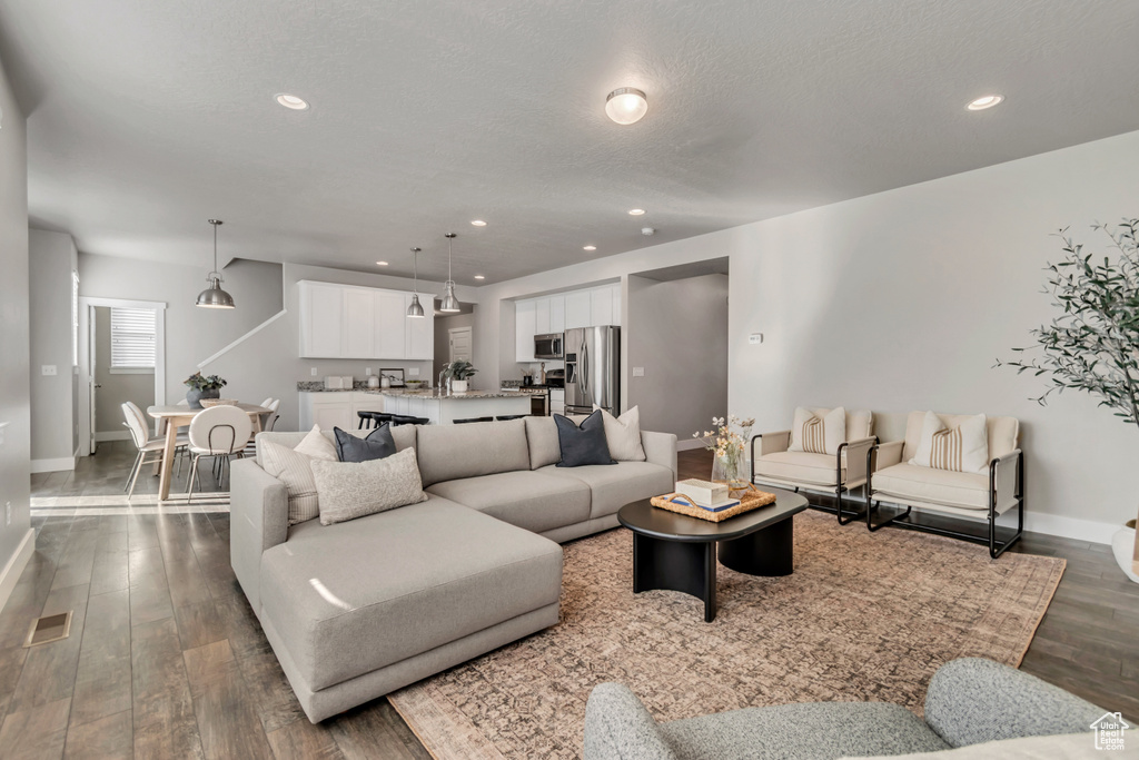 Living area featuring baseboards, dark wood-style floors, and recessed lighting