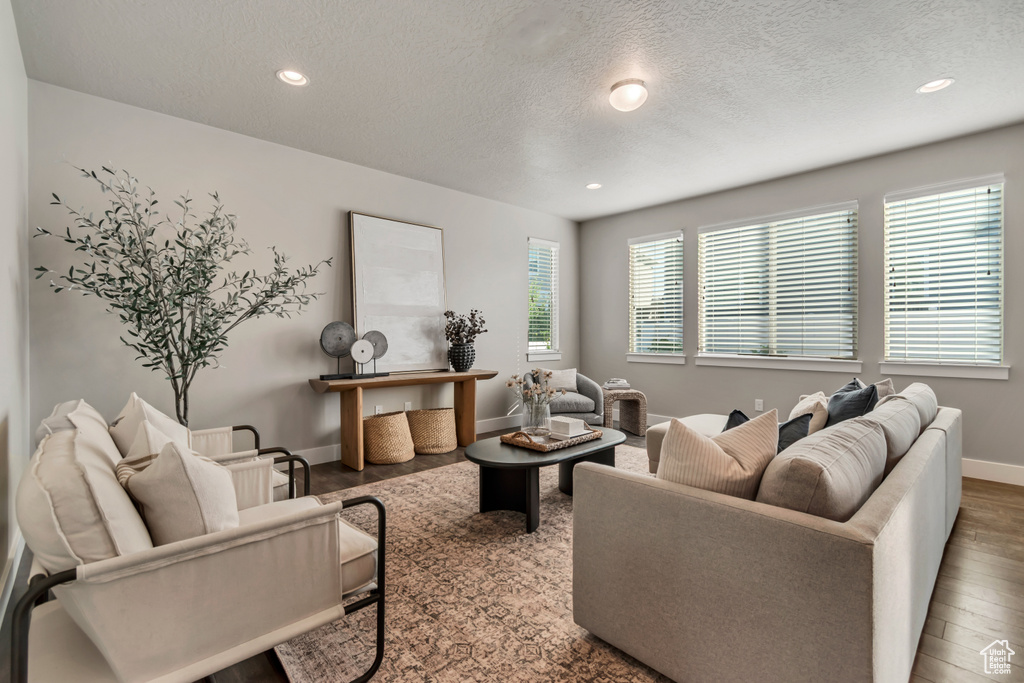 Living room with a textured ceiling, recessed lighting, wood finished floors, and baseboards