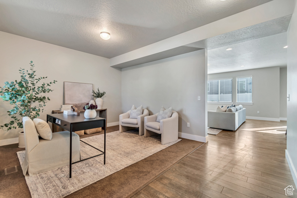 Office area with a textured ceiling, baseboards, and wood finished floors