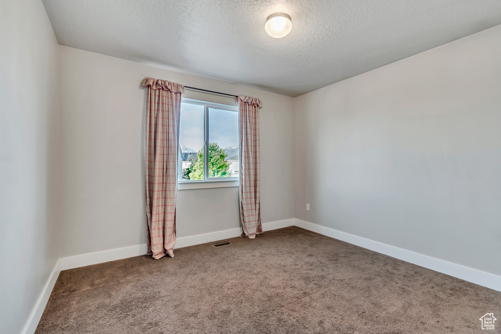 Unfurnished room with carpet floors, a textured ceiling, and baseboards