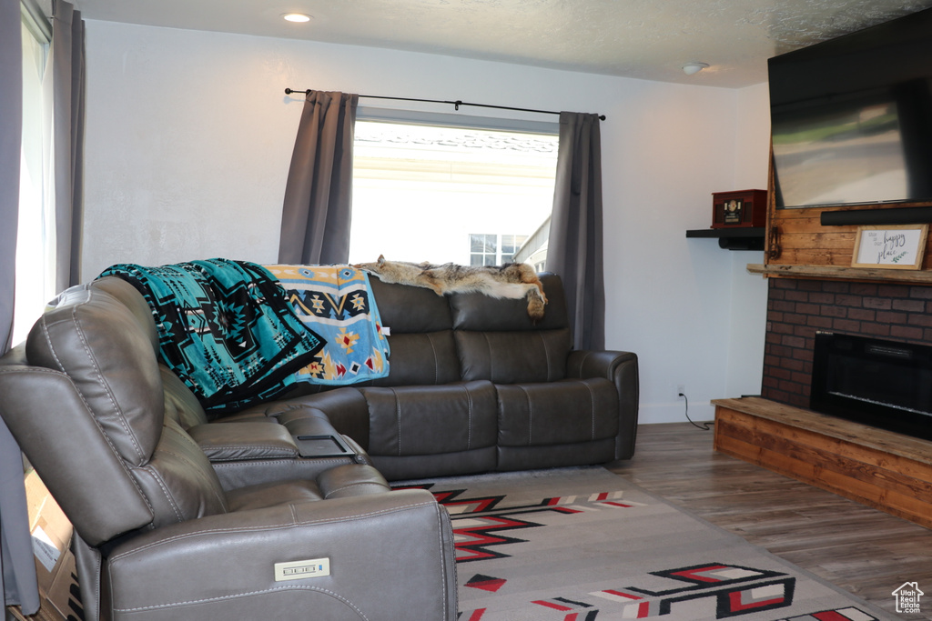 Living area featuring wood finished floors, a brick fireplace, recessed lighting, and baseboards