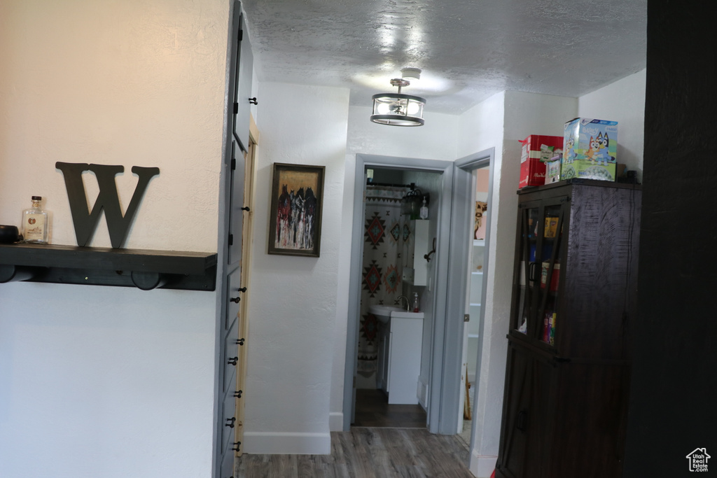 Hall featuring wood finished floors, a textured ceiling, and baseboards