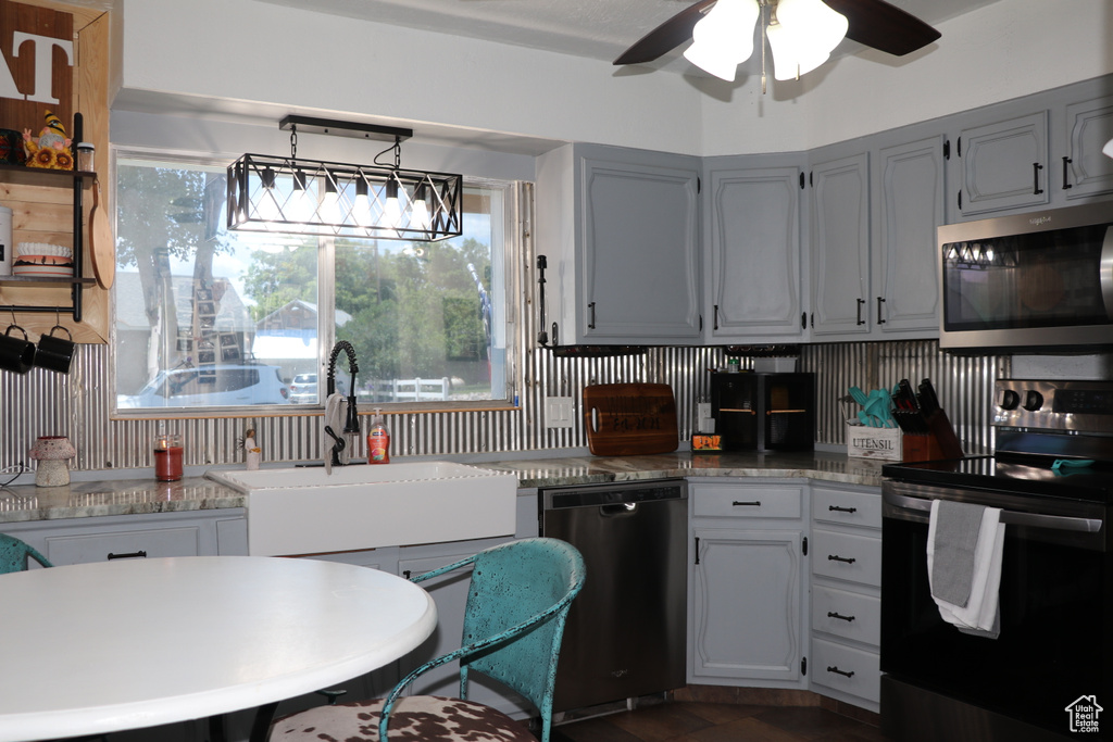 Kitchen featuring stainless steel appliances, a sink, ceiling fan, backsplash, and light countertops