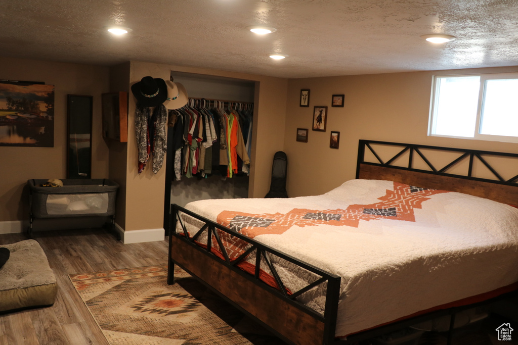 Bedroom with wood finished floors, baseboards, a closet, recessed lighting, and a textured ceiling