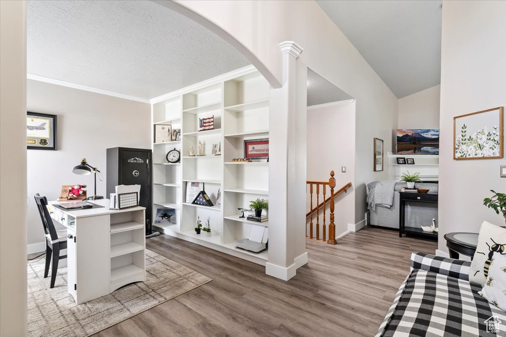 Home office with arched walkways, wood finished floors, baseboards, ornamental molding, and a textured ceiling