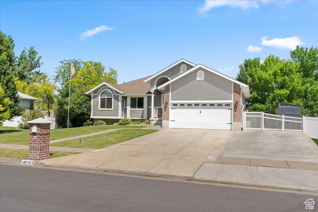 Single story home featuring a garage, driveway, a gate, brick siding, and stucco siding