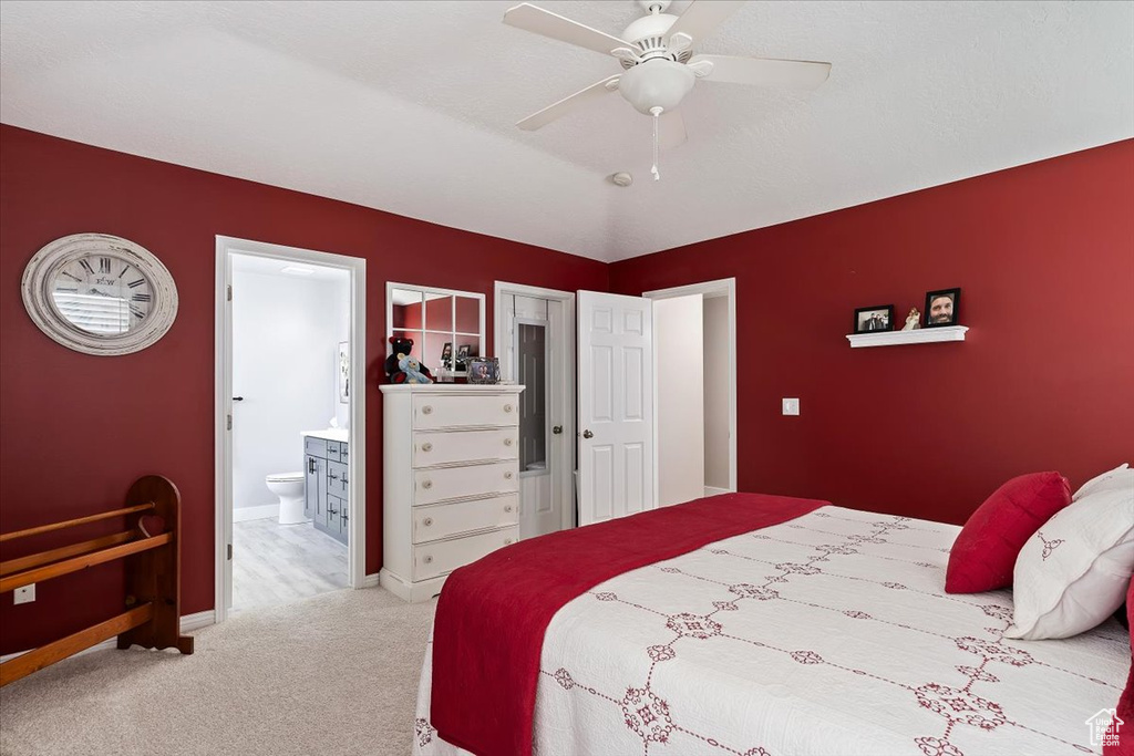 Carpeted bedroom featuring ensuite bath, baseboards, and a ceiling fan