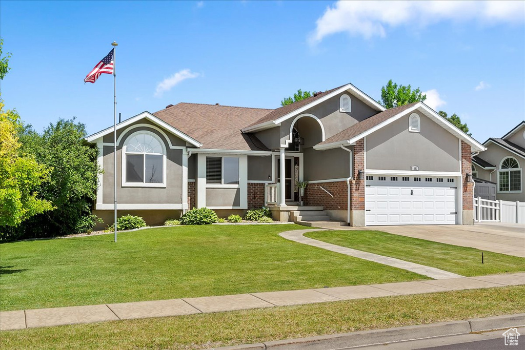 Ranch-style home with an attached garage, stucco siding, brick siding, concrete driveway, and roof with shingles