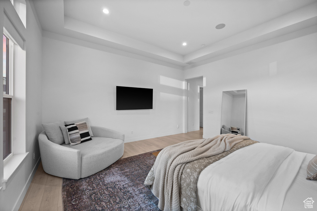 Bedroom featuring a raised ceiling, wood finished floors, recessed lighting, and baseboards